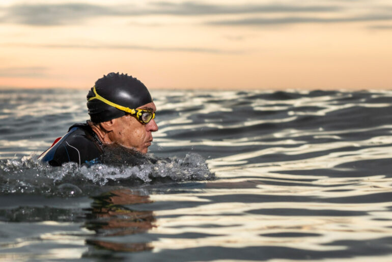 man swimming with goggles in the ocean