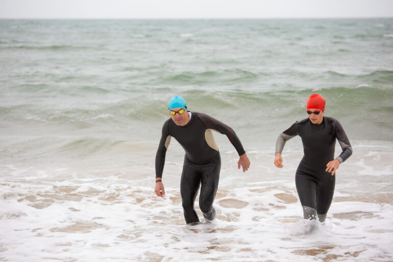 People swimming wearing wetsuits